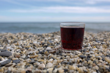 closeup of glass of red wine on the rocky beach