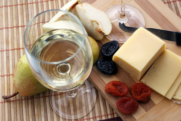 Glasses with white wine and cheese with fruit..