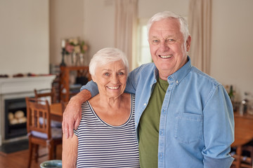 Content senior couple standing happily in the living room