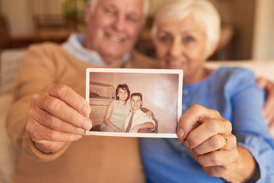 Hands of senior couple holding their youthful photo at home