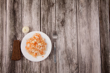Sour cabbage on a plate and black bread on a wooden background