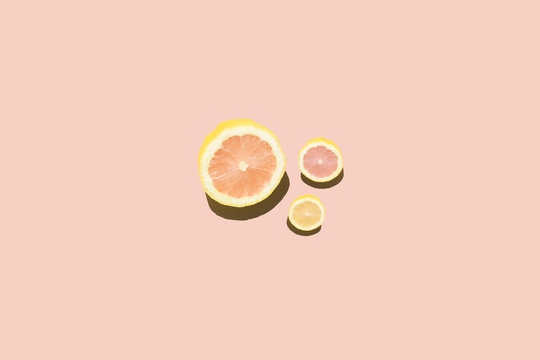 Different sized lemons sliced against pink background, studio shot