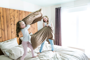 Obraz na płótnie Canvas Portrait kids fighting with pillows in bed