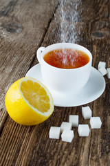 sweet cup of fruit tea with lemon and sugar on a wooden background