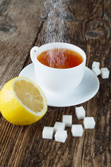 sweet cup of fruit tea with lemon and sugar on a wooden background