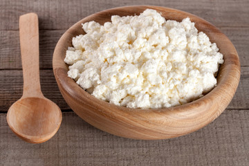 Cottage cheese in a wooden bowl on old wooden background