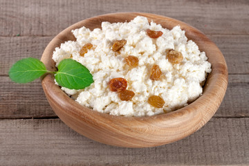 Cottage cheese with raisins in a wooden bowl on a wooden background
