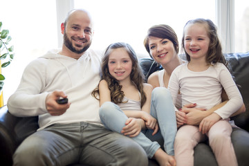 Family sitting in living room watching tv