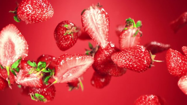 Ripe strawberrys flying in the air on a red background