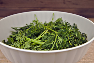 Bio waste-carrot tops in a white plastic bowl