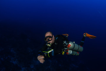 A sidemount scuba diver with perfect trim in the blue water of the Caribbean.  The diver is...