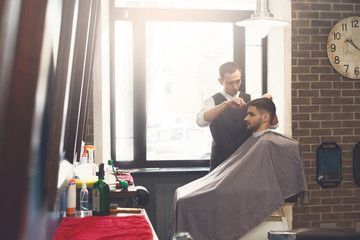 Man getting haircut by hairstylist at barbershop