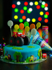 Birthday cake with red car and colorful balloons on top on the bokeh background