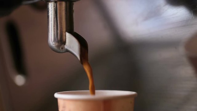 Close up. Coffee machine pouring coffee in to the paper cup. 