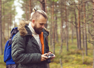 Bearded man hiking in swamps and taking pictures of autumn forest. Camp, adventure, trip and fishing concept.