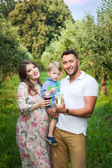 Young attractive family walking in a meadow and drinking juice