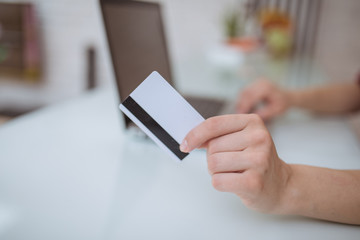 Close up and part of human hand using laptop and holding credit card