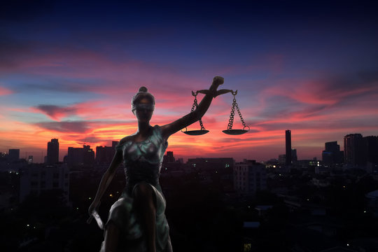 Silhouette of Lady Justice and city in dawn time