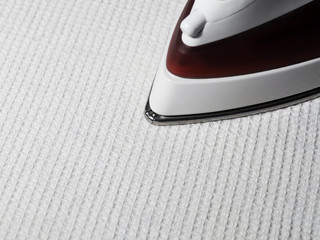 Ironing room. Iron stroking a white waffle fabric.