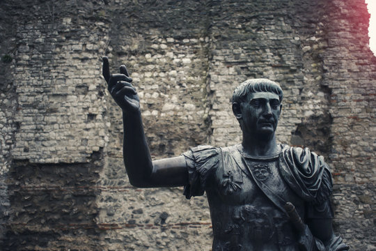 Statue of Roman Emperor Traian in Front of Ancient Wall 