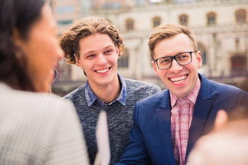 Jolly happy smiling people who sit together, outdoors