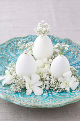 Easter floral decoration with goose egg, orchid flowers and gypsophila paniculata twigs.