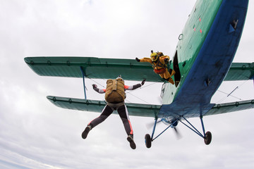 Skydivers with old-school equipment are in the sky.