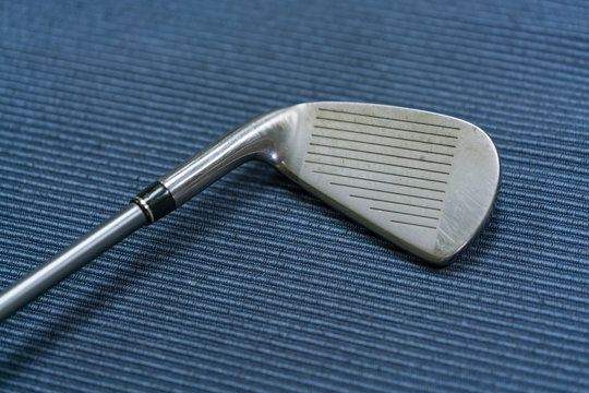 Close up shot of golf club on blue mat background.