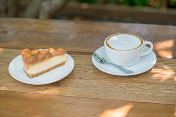 Piece of macadamia cake with capuchino coffee cup on wooden table.