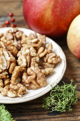 Bowl of walnuts and red apples on wooden table