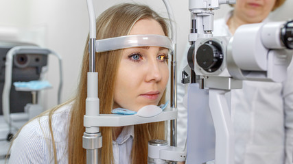 Attentive optometrist examining female patient on slit lamp in ophthalmology clinic