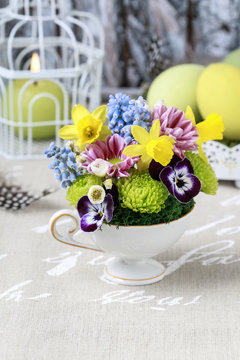 Floral arrangement inside vintage ceramic cup.