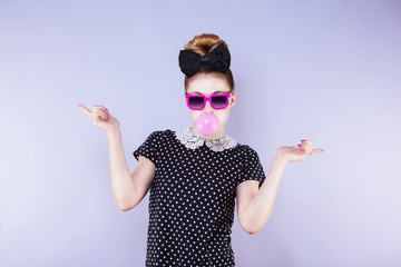 Portrait humoristique d'une jeune femme faisant une bulle de chewing gum les mains sur les cotés