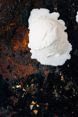 Ball of melted ice cream on black rustic surface.