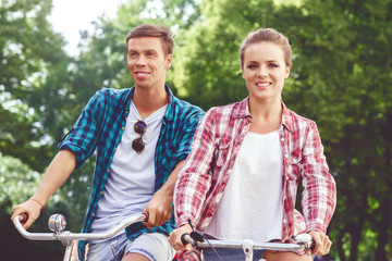 Obraz premium Happy traveling couple riding on bicycles. Boyfriend and girlfriend in old town. Love, relationship, romance concept.