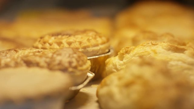 Close up of freshly baked pies on shelf in bakery shop display cabinet