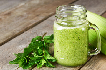 Healthy green smoothie in glass mug on old wooden background