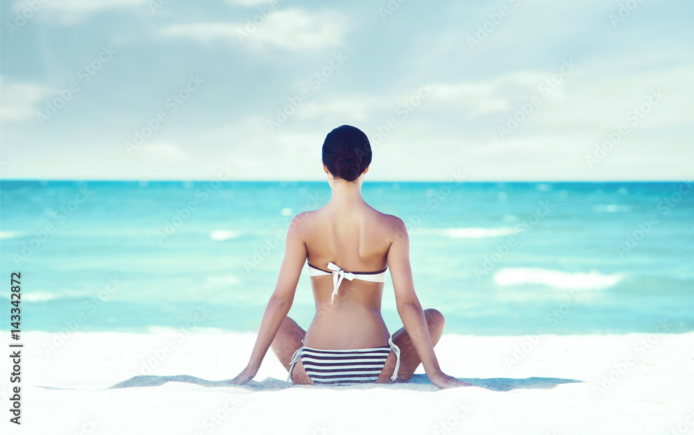 Wall mural young, beautiful and sexy girl meditating on a summer beach. traveling, holiday, vacation, concept.