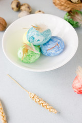 Green, yellow and blue easter eggs on ceramic bowl, bright and airy shot.