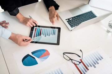 Professional team analyzing bar chart displayed on tablet PC