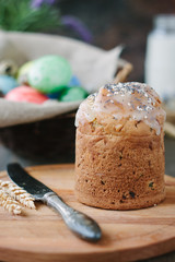 Easter cake standing on board against the basket with easter eggs.