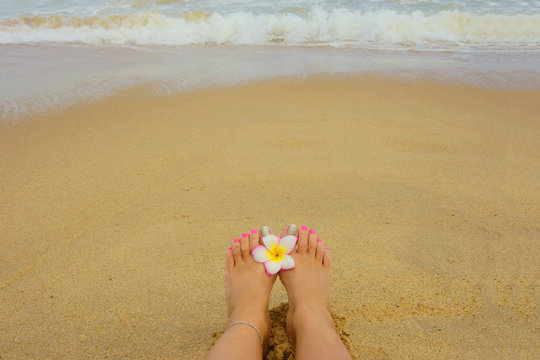 female foot  on the beach, flower