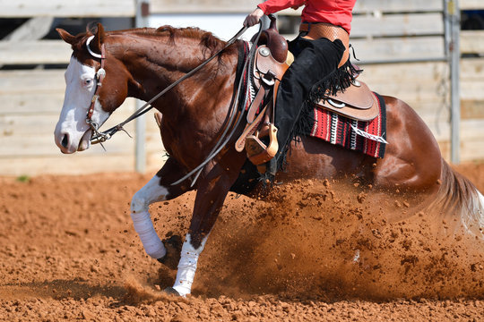 A side view of western rider sliding the horse in the dirt