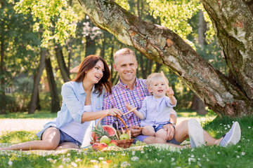 Fototapeta premium Happy family spending time in the park with son holding the pretzel.
