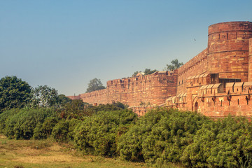 Fototapeta na wymiar View of the Agra Fort with a blue sky and green bushes on the front. Agra Fort is a historical fort in the city of Agra in India. It is also a UNESCO World Heritage site and is about 2.5 km northwest