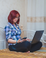 Young Woman with Red Hair Working from Home - Female Entrepreneur Sitting on Bed with Laptop Computer,