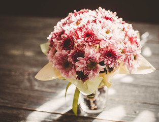 Wedding bouquet from chrysanthemums on a wooden table. Beams of the sun. Flowers for a marriage ceremony. Vintage toning
