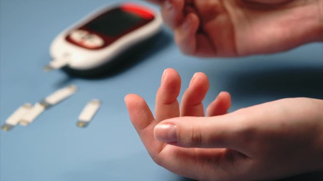 Close up blood sugar test. Woman self-testing for diabetes. Blood sampling for glucometer.