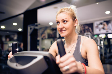 Fototapeta na wymiar Young blonde is having cycling training at gym