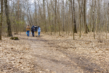 People go on vanishing footpath in forest covered by shriveled leaves
